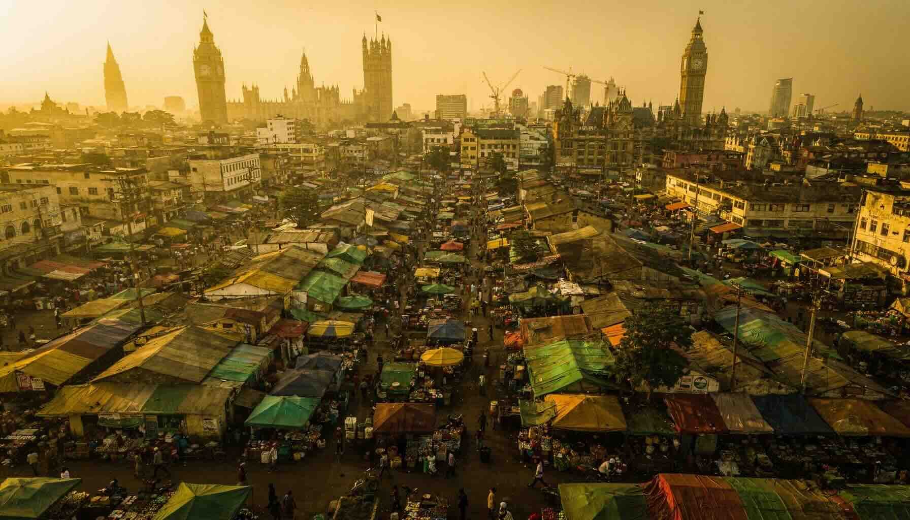 Aerial golden-hour shot of Kumasi's central market from above — dense colourful  canopies, crowds, traders — with a subtle double exposure overlay of a European city  skyline (London or Amsterdam) fading into the scene.